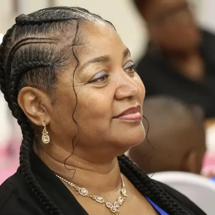 A woman with braided hair listens with a gentle smile