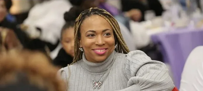 A guest in a soft grey sweater smiles from her seat