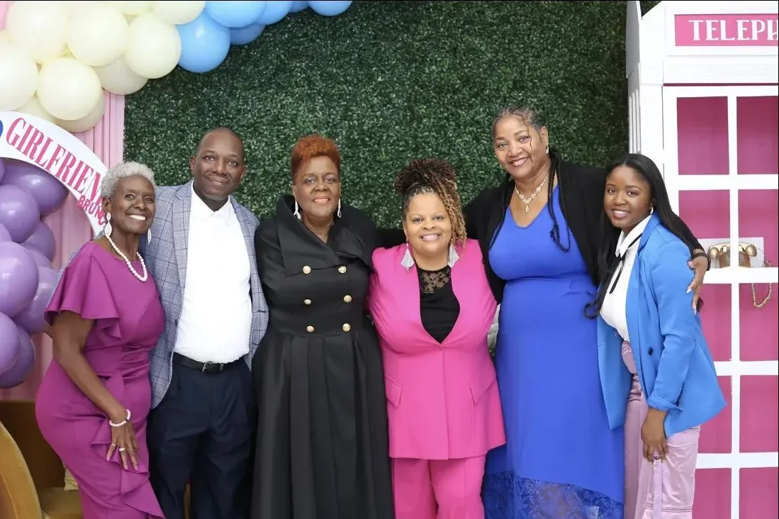 Six members of the Real Girlfriends family pose in front of the balloon wall and pink phone booth