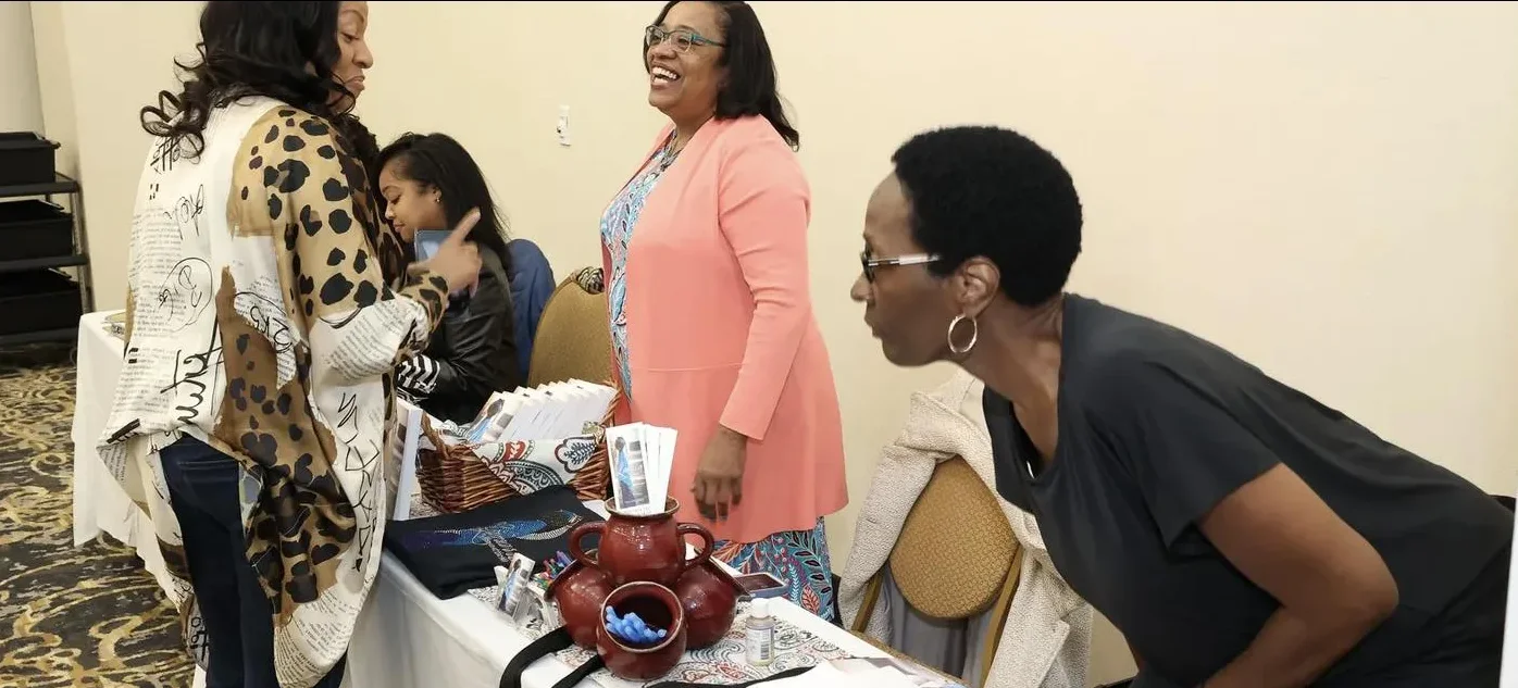 Women laugh together at a vendor table